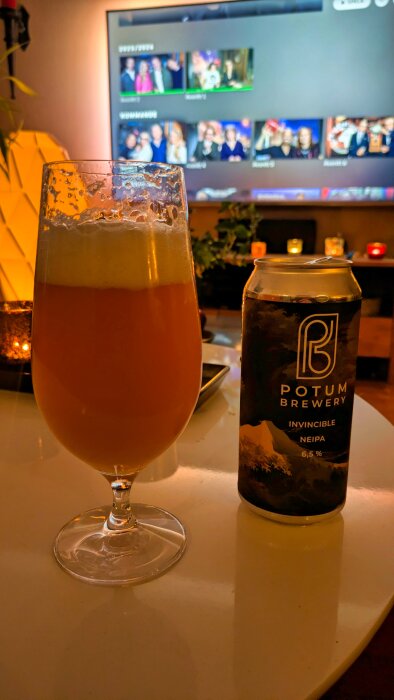 Glas med skummande öl och ölburk med "Potum Brewery Invincible NEIPA" 6,5% framför en TV som visar programmet "På Spåret".