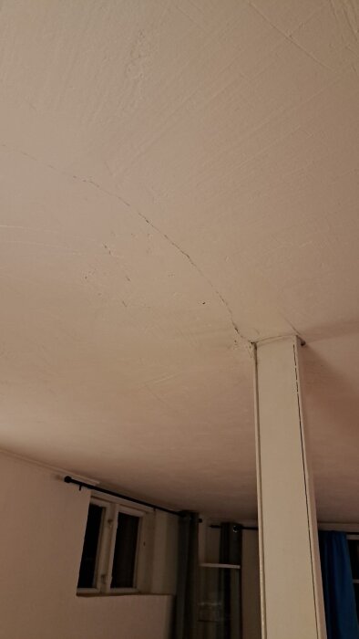 Sprickor i ett källartak av betong i ett hus från 1936, synliga nära en pelare och fönster, eventuell oro för strukturell skada.