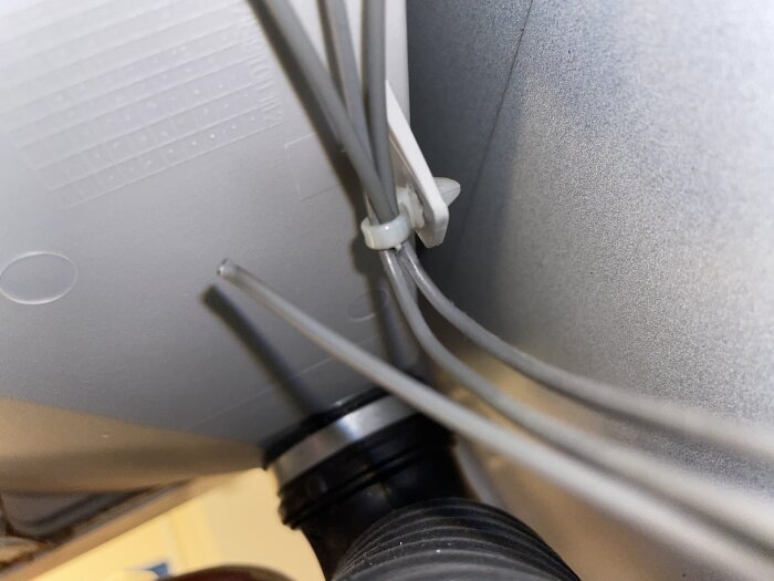 Närbild på flera grå kablar där en kabel är bruten vid tvättmedelsfacket.