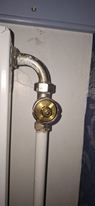 Närbild av ett termostat-givarrör med ett synligt stift och en mutter vid ett element.