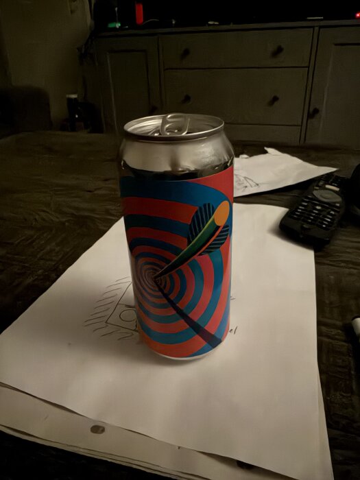 En ölburk med färgglad design och pil som träffar ett mål, står på ett papper.