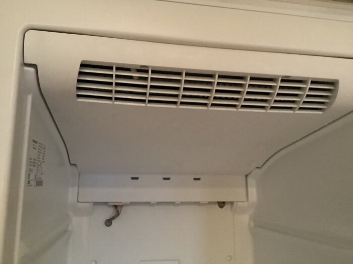 Övre delen av en frys av märket Husqvarna/Electrolux QT3159W, visar kylfläktarnas galler som verkar svårt att ta bort.