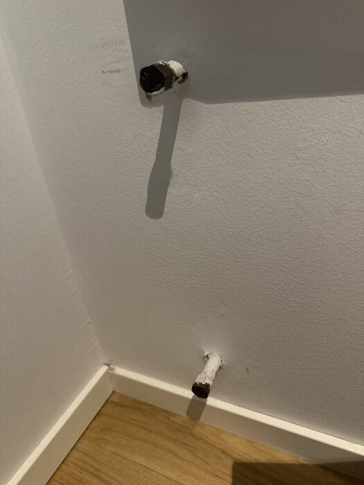 Vita rörstubsändar som sticker ut från en vägg, troligen del av ett frånkopplat radiatorrörsystem i ett hus.