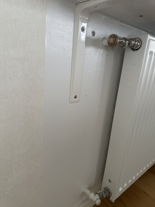 Radiator kopplad till vägg med synliga rör och ventiler, del av diskussion om 1-rörsystem i ett hem.