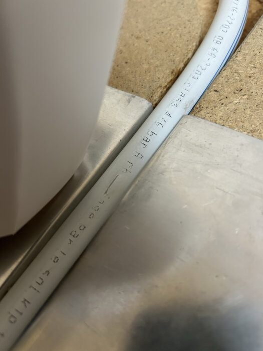 Uponor golvvärmeslang 17mm installerad i spårade spånskivor med eventuell skada från en knivspets.