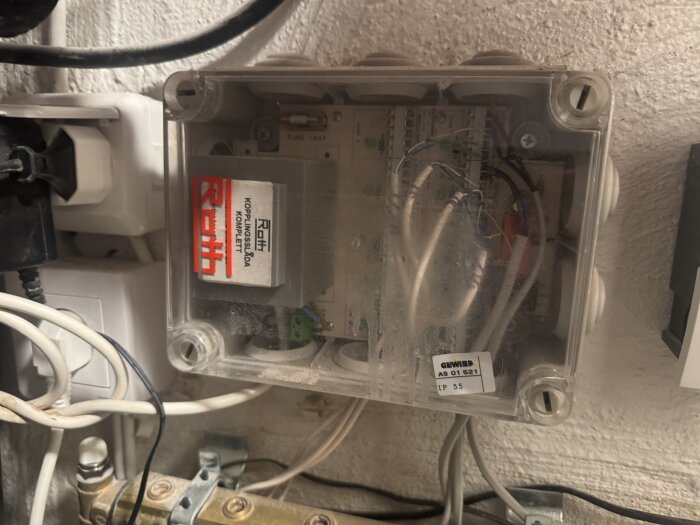 Plastlåda för Roth golvvärmesystem med anslutna kablar och märkning synlig, installerad på väggen.