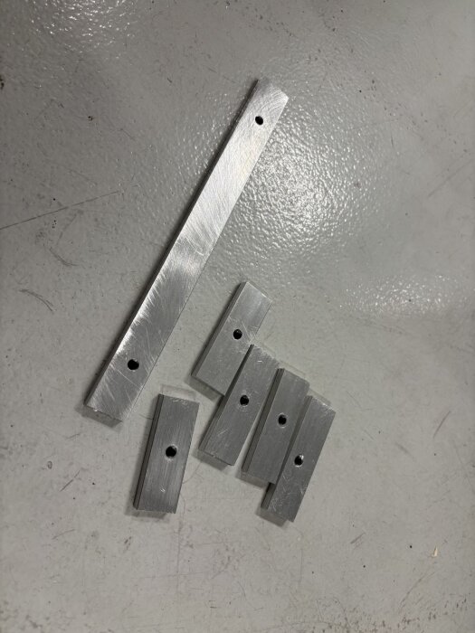 Aluminiumstycken med borrade hål, används som supportpunkter för golvinstallation.