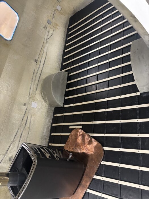 Golvet i en husvagn med monterade asp-ribbor och ett aggregat i ett hörn, med stödstrukturer och delar av väggen synliga.