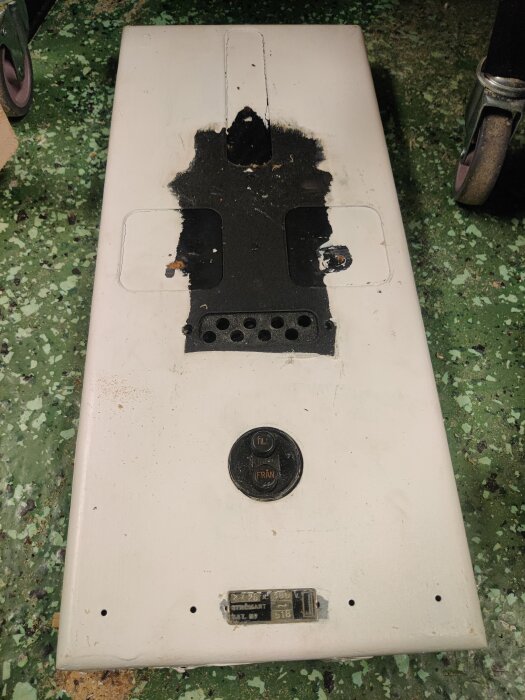 Huvudbrytare med säkringshållare till två huvudsäkringar ligger på ett grönmönstrat golv.