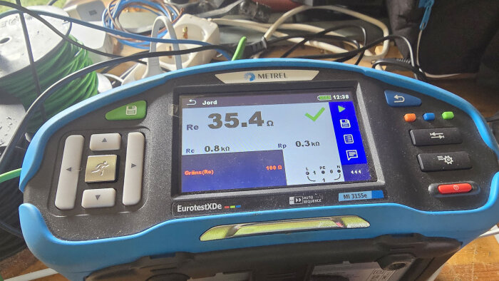 Multimeter visar en jordresistans på 35,4 ohm, med flera kablar i bakgrunden. En del av ett projekt för att installera ödrift och förbättrad jordning.