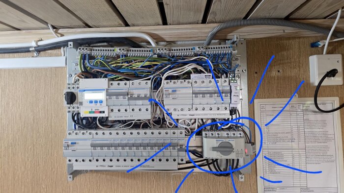 Elcentral med flera kablar och brytare, inklusive en frånskiljare markerad med blå cirkel, installerad för att möjliggöra strömkällaomkoppling.