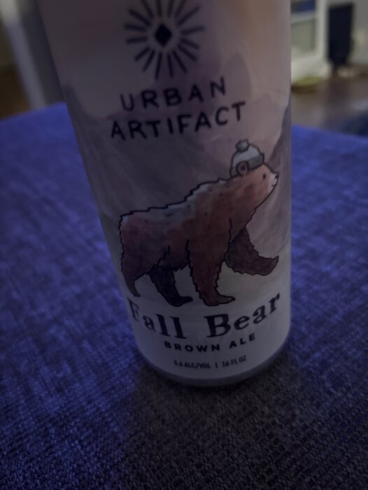Burk med etikett för Urban Artifact Fall Bear Brown Ale, med illustration av en björn med mössa.