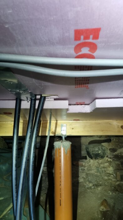 Pem-rör i torpargrund med kablar och isolering ovanför röröppningen, del av fråga om isolering från egen brunn in till huset.