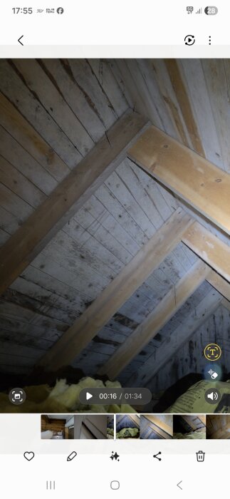 Trätak och bjälkar i ett takvåning med synliga tecken på fukt och mögel, med isoleringsmaterial i förgrunden.