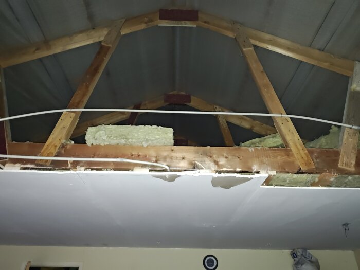 Takkonstruktion med öppnade takstolar i garage för att öka takhöjd; isolering synlig, pågående renovering för ändrad takstolsstruktur.