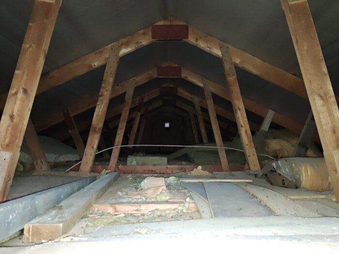 Garagetak med synliga takstolar och isolering, där byggprojekt för ökad takhöjd pågår.