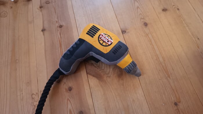 Leksaksskruvdragare i gul och svart design ligger på ett trägolv.