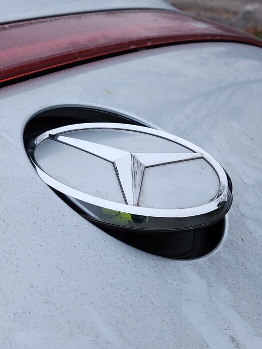Mercedes-bakluckehandtag med logotyp i öppnad position, avslöjat problem med trasig fjäder som förhindrar stängning.