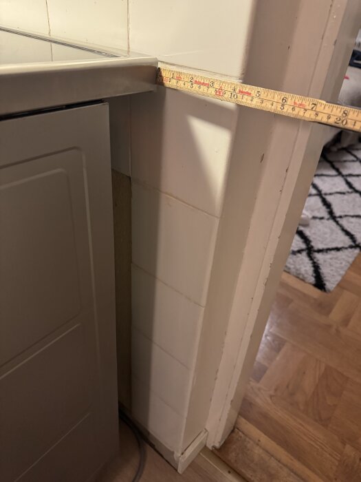 En bredare spis med ett måttband som visar 10 cm utrymme mellan spisen och väggen i ett kök.