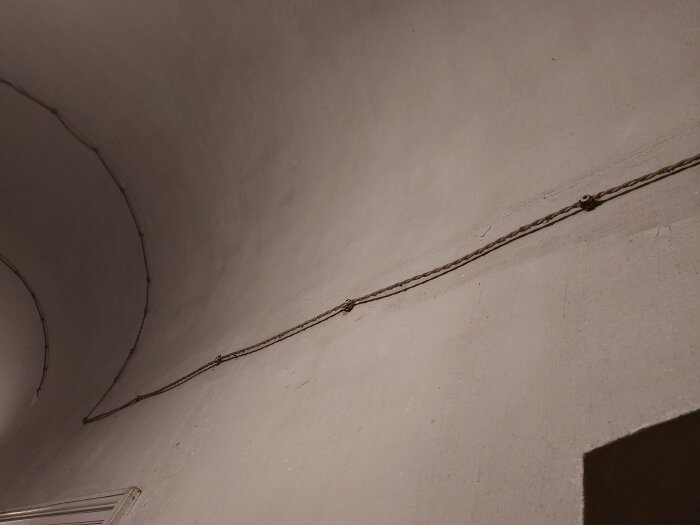 Äldre elektrisk installation med synliga tvinnade kablar på en vägg, delvis moderniserad men kvarlämnad, i ett äldre hem.