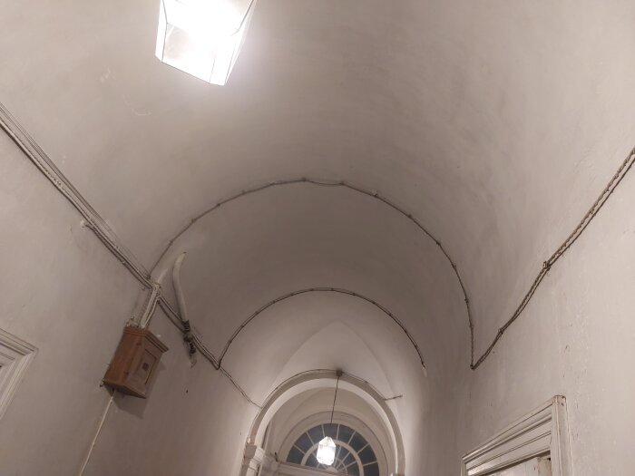 Äldre elektrisk installation med synliga kablar längs välvd takvalv, bevarade trots ny uppdatering.