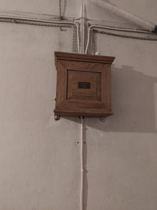 Äldre elinstallation med en trälåda och gamla kablar på väggen.