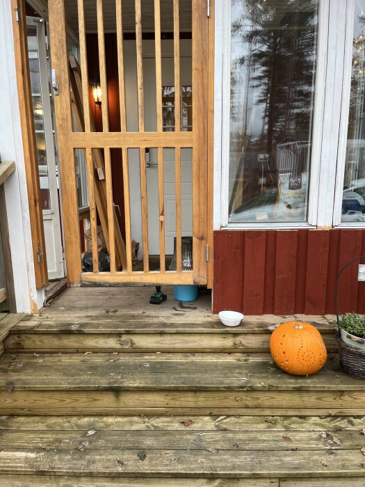 Farstukvist med träspjälor och en pumpa på trappan, förberedd för renovering med nya pardörrar planerade.