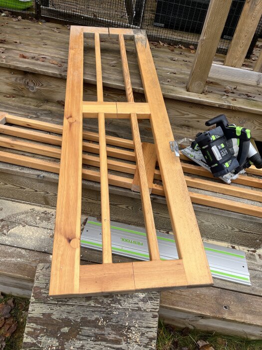 Trädörr under arbete, liggande på trappa med verktyg bredvid. Sedd bakifrån med delning i mitten och verktyg från Festool synligt.