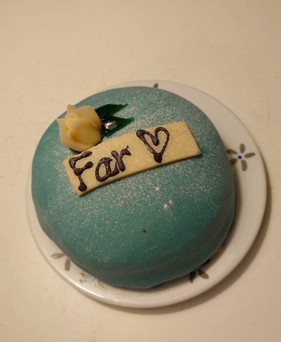 Gröntårta med texten "Far" och en rosa dekoration på ett fat.