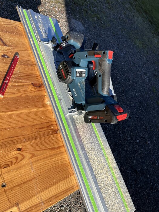 Bosch cirkelsåg på Festool-skena, placerad på ett träbord med sågspån och en röd penna bredvid.