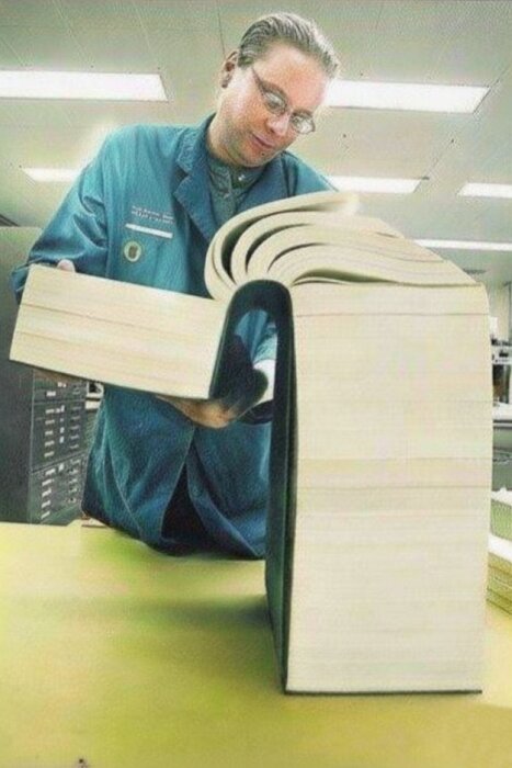 En person bläddrar i en enorm anteckningsbok med många sidor, symboliserande långa projektlistor.