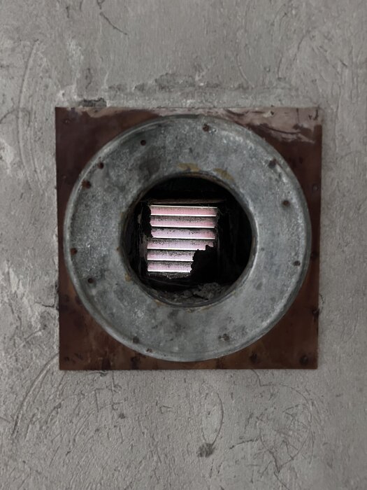 Gammal tallriksventil insatt i en vägg, synlig under köksrenovering, bakgrunden visar rå betongvägg.
