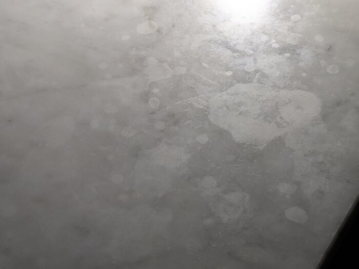 Närbild av marmorskiva med fläckar och reflekterande ljus.