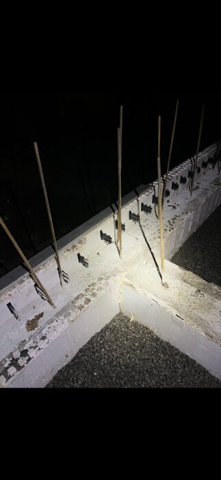 Grundmur i thermomur med stående armeringsjärn, överst fylld med gravel.