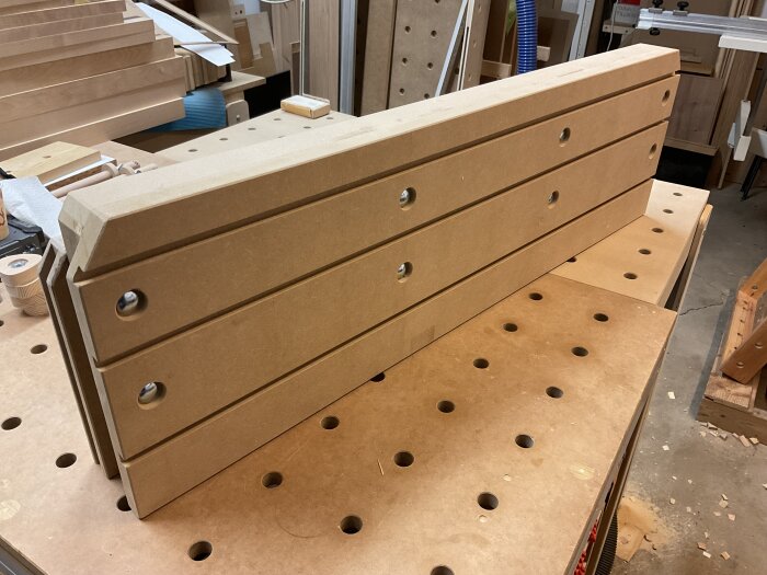 Högt anhåll för justersåg i verkstad, ny version 2.0 med torsion box-konstruktion, monterat och klart, på arbetsbänk med hålmönster i bakgrunden.