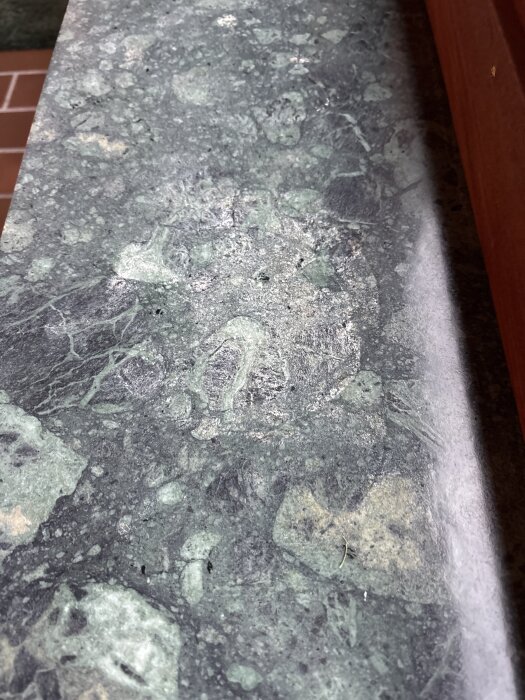 Slipad marmorliknande fönsterbräda i grönt med synliga fläckar efter behandling.