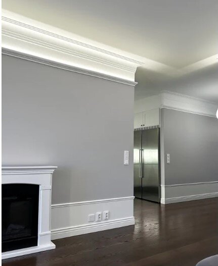 Indirekt belysning under taklist i ett modernt rum med ljusgrå väggar och mörkt golv, inspiration för dimbar belysning i en bostad.