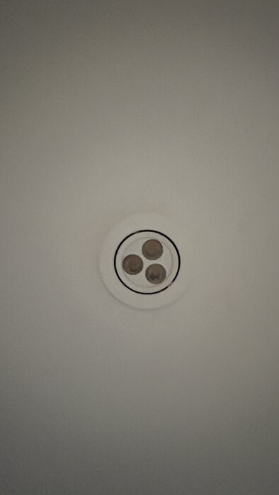 Inbyggd vit downlight med tre ljuskällor i ett tak, ses rakt underifrån.