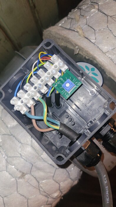 Elektrisk kopplingsbox med flera anslutna kablar och en potentiometer monterad på ett kretskort, märkt "Systemair SY 17".