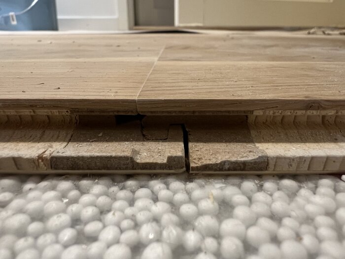 Närbild på parkettgolv med synlig sammanfogning och skumbollsliknande underlag.