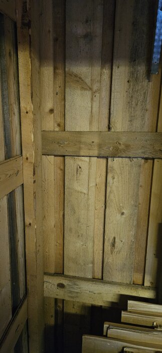 Trästomme i ett uthus med synliga reglar och brädor, diskussion om tilluft och väggisolering i samband med renovering.