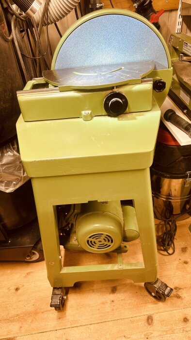 Grön Ulmia tallriksslipmaskin med enfasmotor, placerad på trägolv. Maskinen har en stor rund slipyta och en motor undertill.