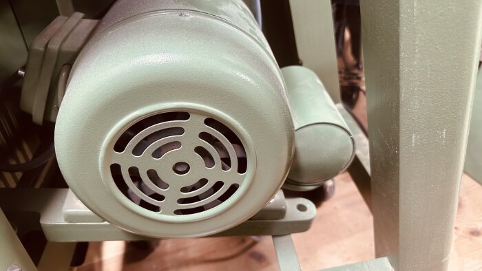 Grön enfasmotor på en Ulmia tallriksslip med synlig kondensatorburk på sidan.