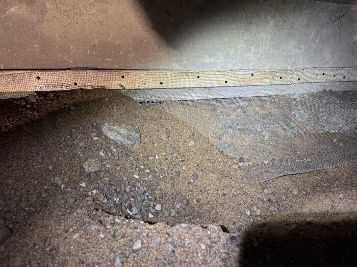 Jordig krypgrund med fastskruvad järntrådduk vid glespanel för att förhindra gnagare.