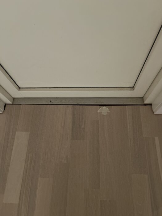 Bild på golv ansluten till en altandörr med en tröskel, golv och dörr i ljusa färger, fokus på övergången.