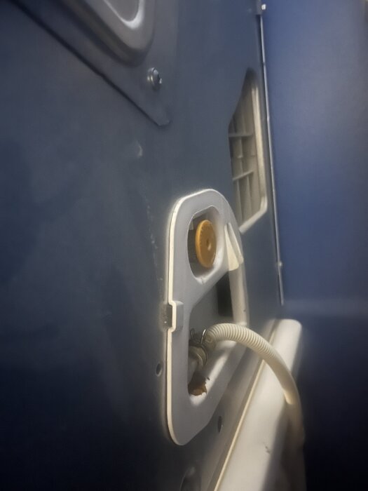 Baksidan av torktumlare med vit ram och gul knapp, kabel ansluten.