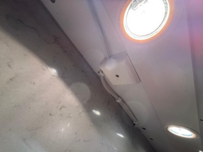 Armatur över diskbänk med tre infällda lampor och en fyrkantig elektrisk dosa, möjlig transformator, synlig mot vit bakgrund.