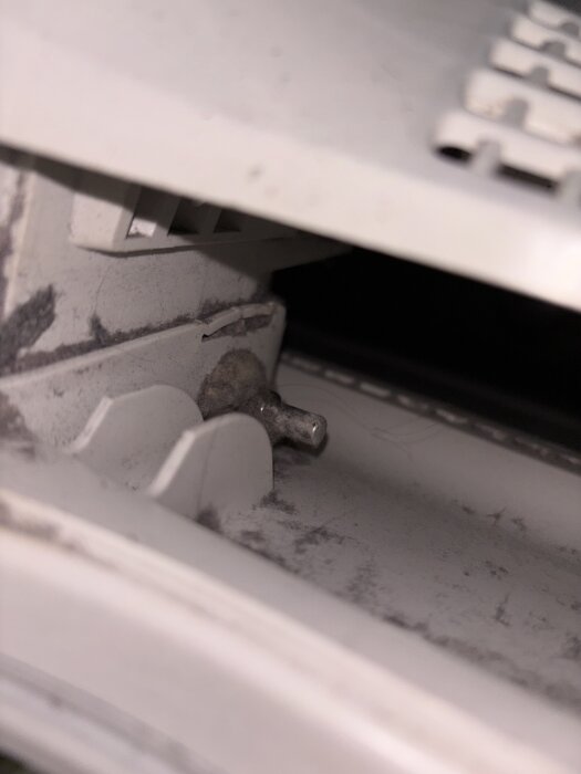 Vit inre del av apparat med en liten spak som misstänks vara en sensor.