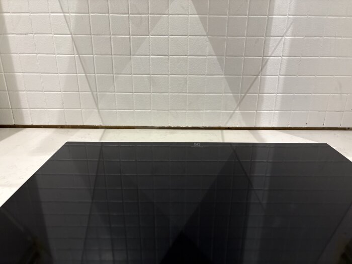 Nyinstallerad stenskiva i kök med glipa mot kaklad vägg bakom spisen, saknas stopp i nederkant; lösningsförslag med bottningslist och fog diskuteras.