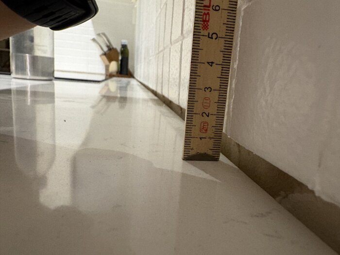 Linjal mäter glipa mellan ny stenskiva och vägg i kök.